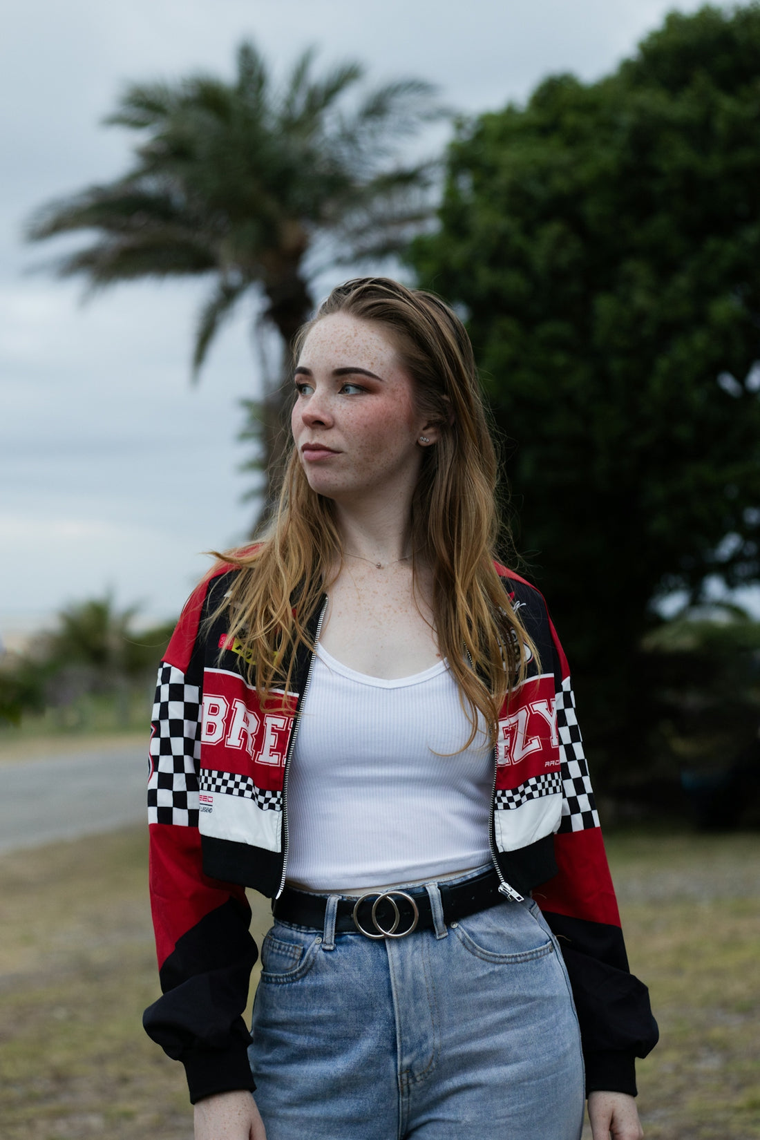 A woman standing in a field wearing a red, white and black jacket
