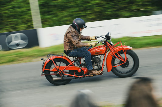 Man riding a vintage red motorcycle on a road