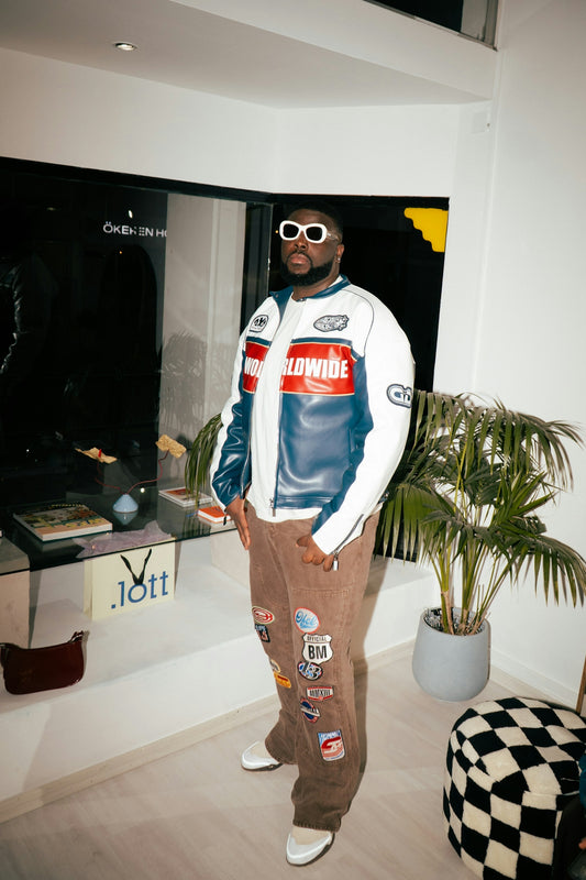 Man wearing a racing jacket and patched pants.