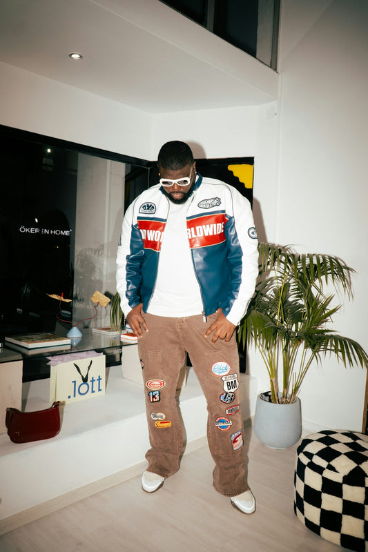Man wearing a racing jacket and patches on-trend pants.