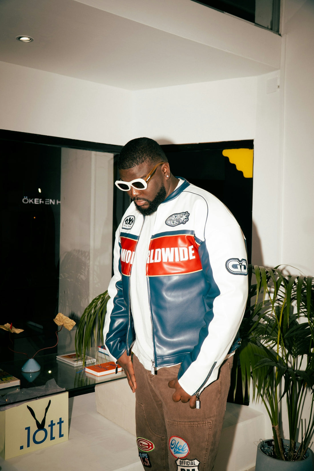 Man in racing jacket and sunglasses indoors